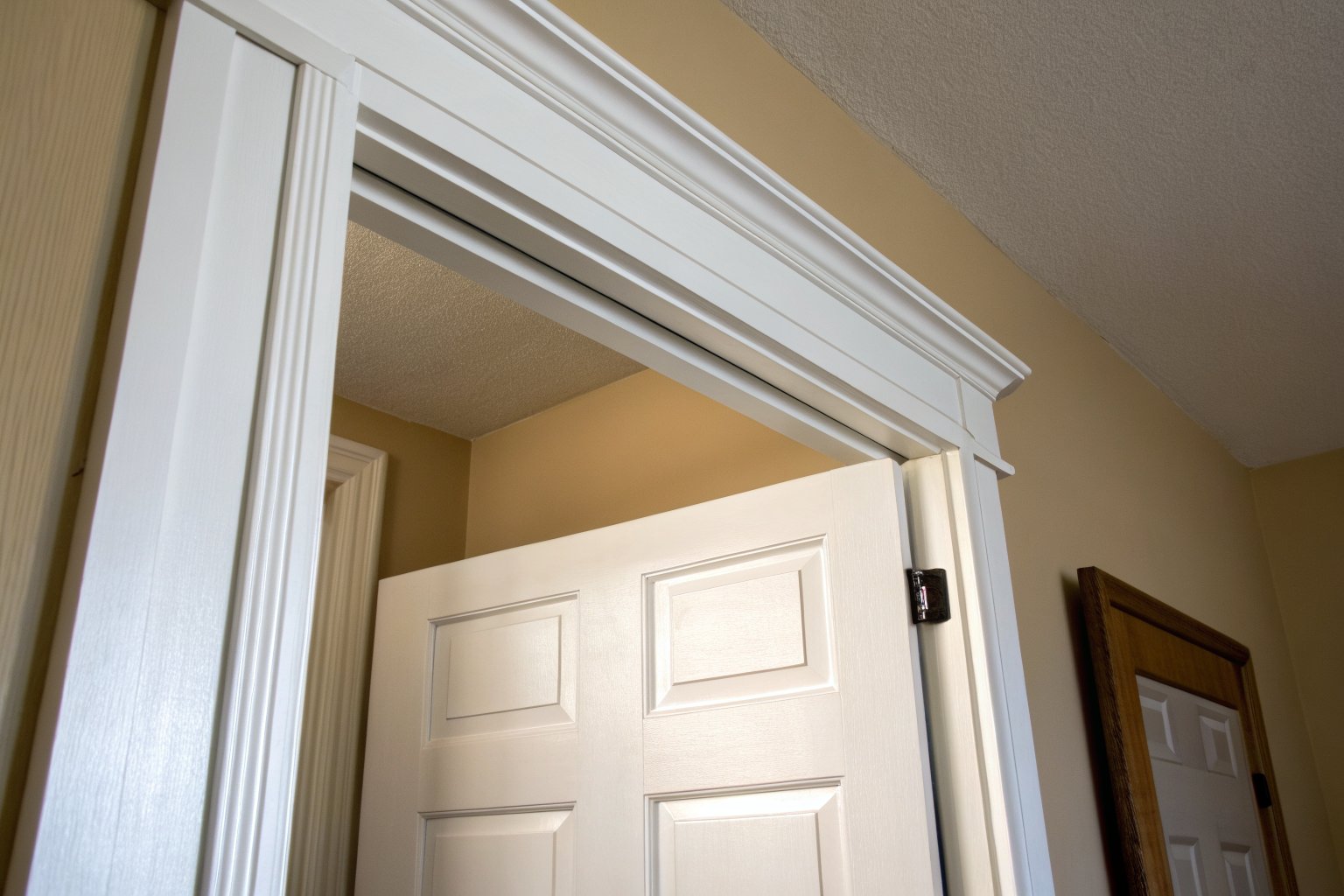 White paneled door hanging low in its frame, leaving a wide gap under the top of the frame